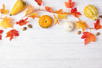Autumn leaves and mini pumpkins over white wooden background, copy space, top view