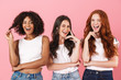 © Drobot Dean - Positive young three multiethnic girls friends posing isolated over pink wall background winking.