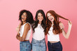 © Drobot Dean - Cheery smiling positive young three multiethnic girls friends posing isolated over pink wall background.