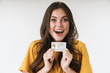 © Drobot Dean - Image of astonished brunette woman wearing casual clothes smiling and holding credit card