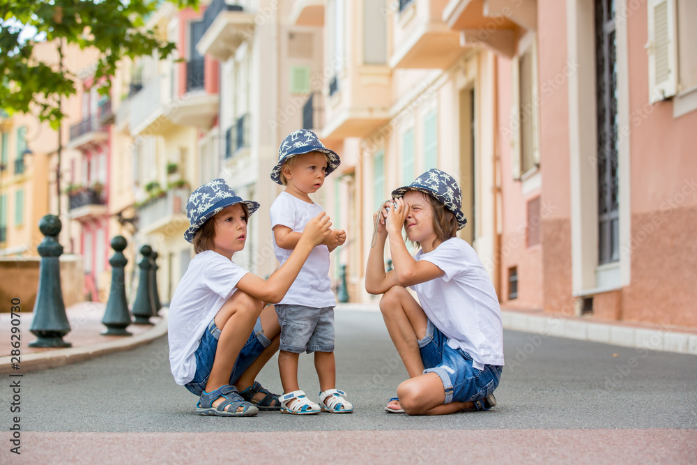 Obraz na płótnie Children taking pictures on a narrow street with houses in Monaco-Ville, Monaco on a cloudy day w salonie