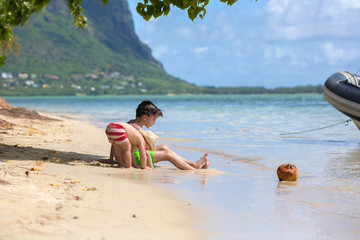 Poster - Sweet child, sit on the shore on the beach with coconut, enjoying beautiful day on le morne island