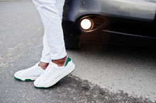 Close Up Sneakers In African Man At White Pants Against Car.