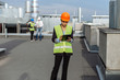 © SpoialaV - On the rooftop of construction site beautiful African engineer make a conversation with some worker using the tablet.