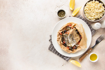 Wall Mural - Fillet of white fish (Pollock, cod, sea bass, Dorada) with olives, tomatoes and lemon, baked in parchment. Traditional French food fish papillot and bulgur