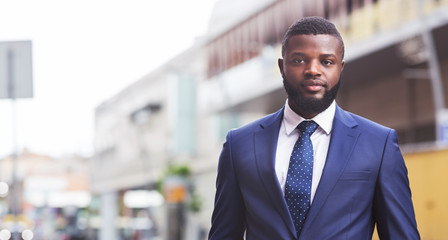 Serious millennial employee posing to camera against cityscape