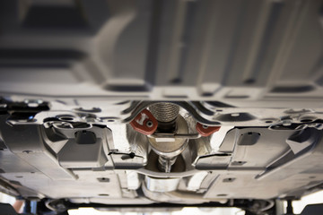 The car is lifted on a lift in a car service. View of the car from below. Focus in the center. Artistic blur.