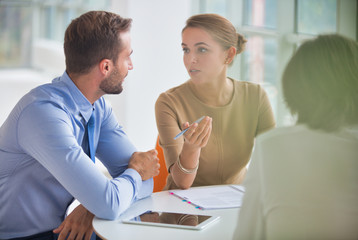 Wall Mural - Young colleagues discussing over document at table during meeting in new