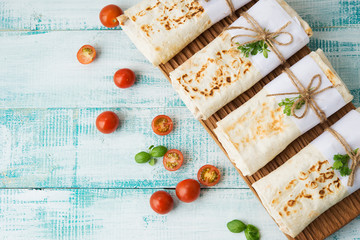 Traditional Mexican food burritos with beans and vegetables. Vegetarian rolls with red beans and vegetables lie on an aged wooden table.