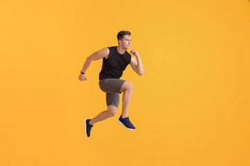 Wall Mural - Running young man on color background