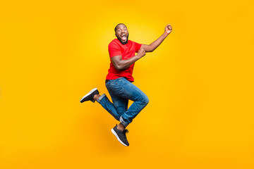 Wall Mural - Full length body size photo of black man wearing red t-shirt having caught something invisible and now dragging it while isolated with yellow vivid background