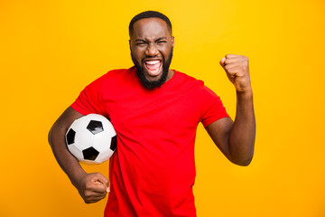 Wall Mural - Photo of soccer team trendy african black funny captain wearing red t-shirt holding soccer ball prepared to win local cup while isolated with yellow background