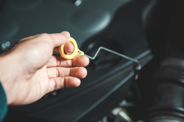 man worker with car oil dipstick