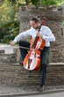 Young man playing cello outside. Cellist playing classical music on cello