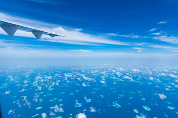 Aircraft wing flying over the blue clouds.