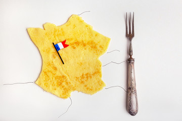 French cuisine concept pancake in form of France with French flag on white table with vintage fork