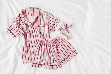 Pajamas sleeping kit. Classic pink sleep dress with stripes in bed. Good morning concept. Flat lay, top view