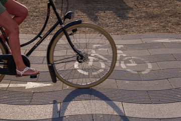 Wall Mural - Close up view of bicycle lane symbol and cyclist ride bicycle on promenade riverside of Rhein River in Düsseldorf, Germany. Cycling friendly city in europe. Eco friendly mobility transportation.