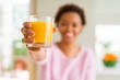 © Krakenimages.com - Young african american woman driking orange juice at home with a happy face standing and smiling with a confident smile showing teeth