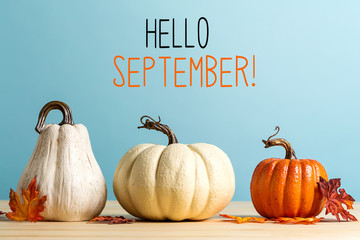 Wall Mural - hello september message with pumpkins on a blue background
