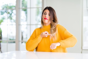 Canvas Print - Young beautiful woman wearing winter sweater at home In hurry pointing to watch time, impatience, upset and angry for deadline delay