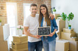 © Krakenimages.com - Beautiful young couple moving to a new house, smiling very happy holding blackboard with our first home text