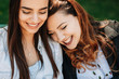 © Strelciuc - Close up portrait of a charming plus size women with long red curly hair laughing while leaning her head on her girlfriend which is also smiling outside.
