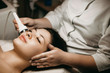 Side view portrait of a charming caucasian female doing anti acne electroporation therapy in a wellness center.