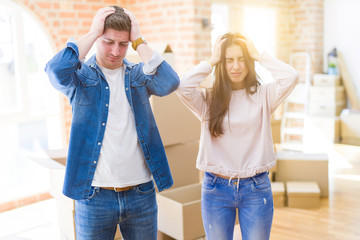 Poster - Beautiful young couple moving to a new house suffering from headache desperate and stressed because pain and migraine. Hands on head.