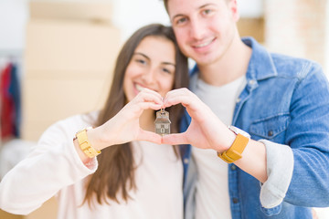 Poster - Beautiful young couple hugging in love and showing keys of new house, smiling happy moving to a new apartment