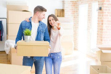 Poster - Beautiful young couple hugging in love and showing keys of new house, smiling happy moving to a new apartment