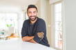 © Krakenimages.com - Handsome hispanic man wearing casual sweater at home happy face smiling with crossed arms looking at the camera. Positive person.