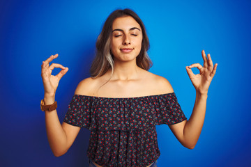 Poster - Young beautiful woman wearing floral t-shirt over blue isolated background relax and smiling with eyes closed doing meditation gesture with fingers. Yoga concept.