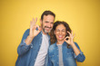 © Krakenimages.com - Beautiful middle age couple together wearing denim shirt over isolated yellow background smiling positive doing ok sign with hand and fingers. Successful expression.