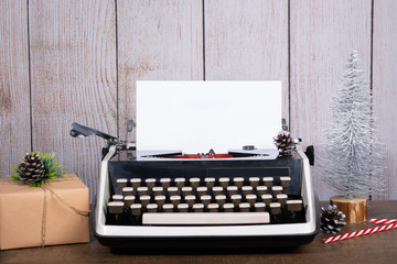 Fototapete - Retro typewriter with a blank sheet of paper for text. Dark Christmas and New Year background. Mock up, Copy space with gifts and white Christmas tree.
