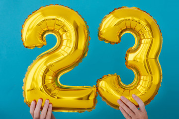 Gold foil number 23 twenty three celebration balloon on blue background