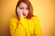© Krakenimages.com - Young redhead woman wearing winter sweater standing over isolated yellow background thinking looking tired and bored with depression problems with crossed arms.