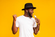 © Prostock-studio - Happy african man in hat singing into smartphone like microphone
