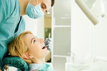 Wall Mural - Dentist looking the teeth of the patient girl