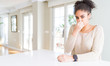 © Krakenimages.com - Beautiful young african american woman with afro hair sitting on table at home smelling something stinky and disgusting, intolerable smell, holding breath with fingers on nose. Bad smells concept.
