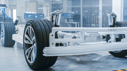 Concept of Authentic Electric Car Platform Chassis Prototype Standing in High Tech Industrial Machinery Design Laboratory. Hybrid Frame include Tires, Suspension, Engine and Battery. 