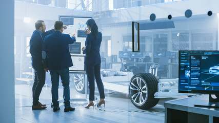 Poster - Diverse Team of Design Engineers are Working and Discussing Something on a Interactive Whiteboard Next to an Electric Car Chassis Prototype. In High Tech Laboratory Facility with Vehicle Frame.