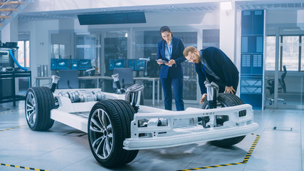 Poster - Automotive Design Engineers Working on Electric Car Chassis Prototype. In Innovation Laboratory Facility Concept Vehicle Frame Includes Wheels, Suspension, Engine and Battery.