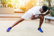 © twinsterphoto - Athletic African American man in blue sneakers doing stretching exercise while training in park on sunny day