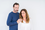 Fototapeta  - Beautiful middle age couple in love over isolated background skeptic and nervous, frowning upset because of problem. Negative person.