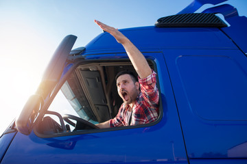 Shot of mad and nervous professional truck driver having arguing in traffic and yelling at someone. Transportation traffic problems.