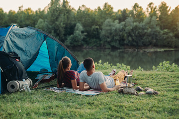 Wall Mural - young couple enjoying camping outdoor by the river