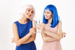 © Drobot Dean - Portrait of two happy young women wearing blue and pink wigs drinking champagne while clinking glasses