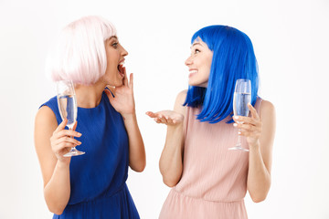 Sticker - Portrait of two excited women wearing blue and pink wigs talking while drinking champagne