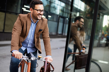 happy young stylish businessman going to work by bike